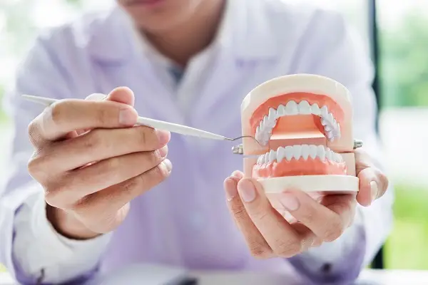 A man showing a replica of a tooth for dental replacement